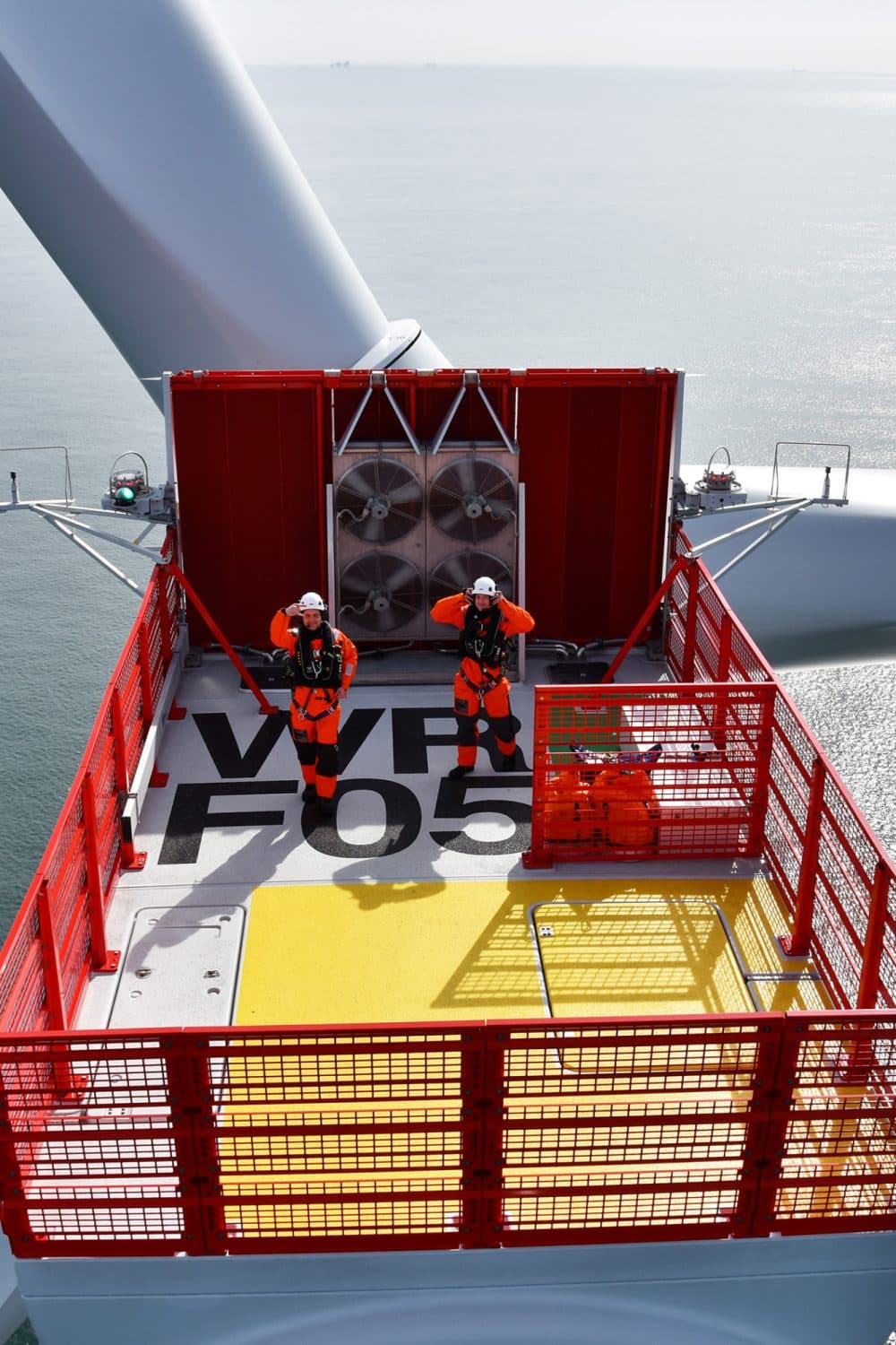 View from above of men waving on a wind turbine